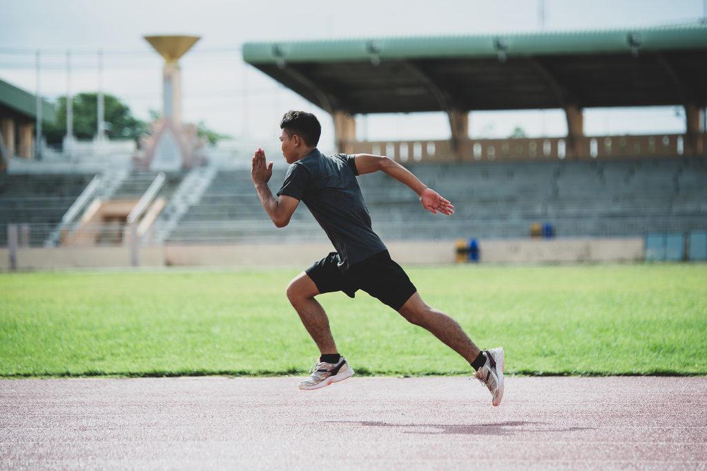 Athlete sprinting on red running track in stadium