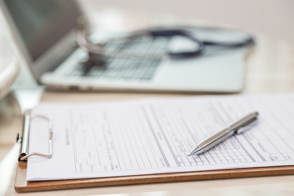 Clipboard with insurance claim forms and a pen for submitting sport physiotherapy treatment expenses 