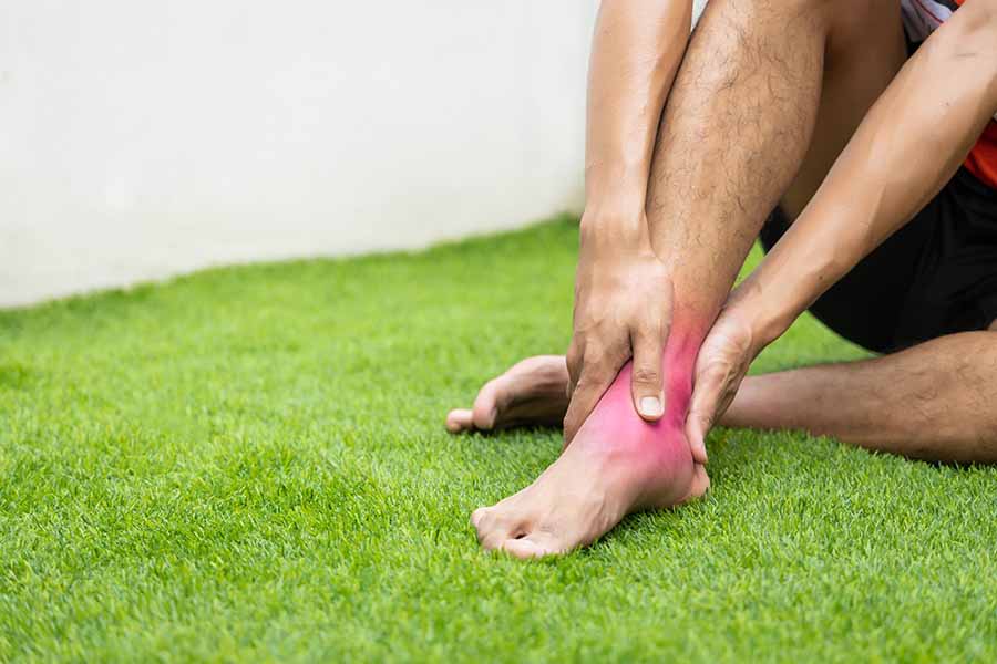 holding injured sprained ankle